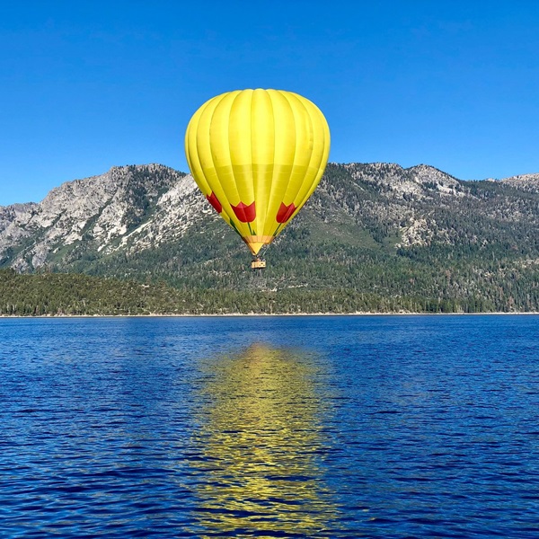 Marvel at the vibrant turquoise hues and the snow-capped peaks reflected on Lake Tahoe as the balloon hovers over its surface.  
