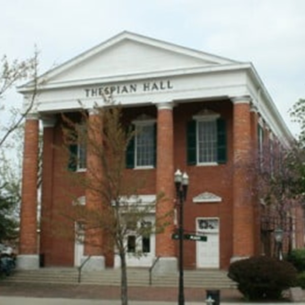 The theater's architectural style is Greek Revival, characterized by its symmetrical facade, two-story structure, and portico adorned with four unfluted Doric columns. 